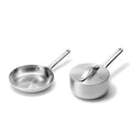 The Caraway Stainless Steel Mini Fry Pan & Mini Sauce Pan Duo features a sleek, polished finish. The non-toxic fry pan with an extended handle is on the left, and the lidded saucepan with a matching handle is on the right, all set against a plain white background.