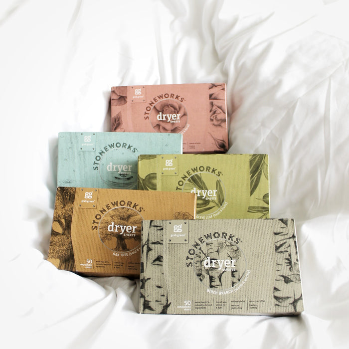 Five vibrant grab green Stoneworks Dryer Sheets - Birch Branch boxes, made from recycled paper, rest on soft white fabric. The boxes come in peach, blue, brown, green, and gray. Each labeled with dryer, contains 50 sheets to soften clothes and reduce static cling.