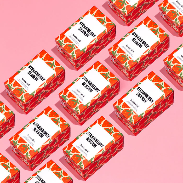 Rectangular boxes labeled Strawberry Season feature red strawberry patterns in diagonal rows on pink backgrounds, reflecting the natural aroma of Homesicks soy wax candle.