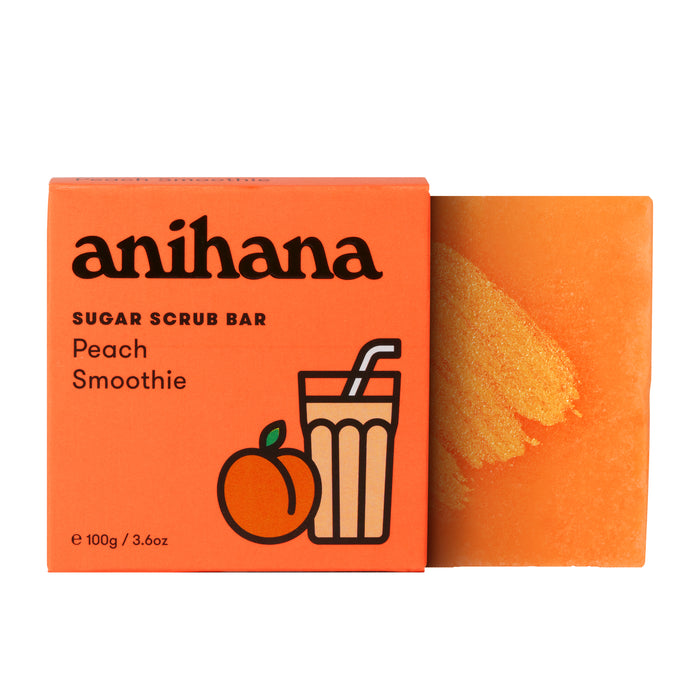 An orange box labeled "Anihana Sugar Scrub Bar" sits next to the orange scrub bar, gently exfoliating with coconut oil. The packaging is decorated with peach and smoothie glass illustrations.