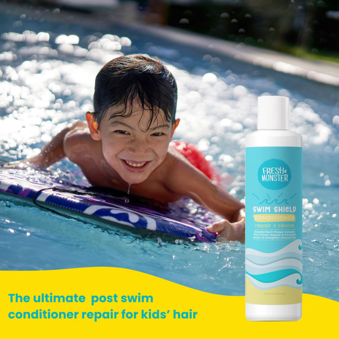 A young boy smiles while riding a boogie board in a pool, with Fresh Monster Swim Shield Chlorine Repair Conditioner beside him. Text reads: The ultimate harsh chemical-free swimmer’s hair repair for kids’ hair.