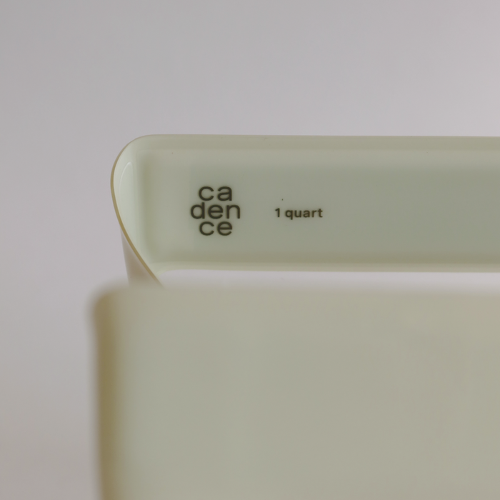 A close-up of a white Cadence container called The Parcel with a minimalist, clean design and 1 quart label—TSA-approved and ideal for travel—set against a softly blurred background.