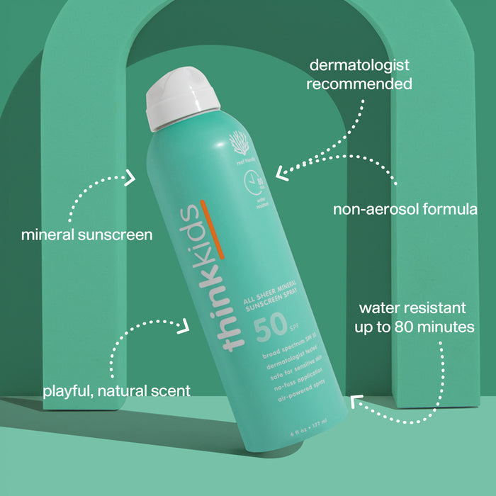 A teal can of thinksun thinkkids SPF 50 All Sheer Mineral Sunscreen Spray stands upright against a green arch. Text features: dermatologist recommended, non-aerosol, water resistant, reef-friendly kids sunscreen with a natural scent.