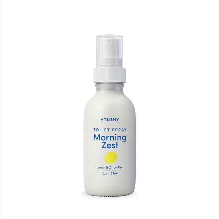 A 2oz (59ml) white TUSHY Toilet Spray labeled Morning Zest with lemon & citron peel, a lemon graphic, and clear spray top. Helps eliminate odors and freshen up after use.