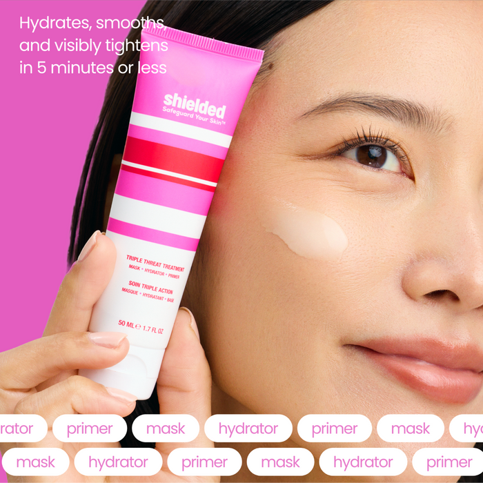 A woman applies Shielded Beauty’s Triple Threat Treatment from a pink and white tube to her cheek. Text: Hydrates, smooths, and visibly tightens in 5 minutes. Enjoy clean beauty with this hydrating primer for instantly refreshed skin.