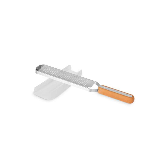 The Full Circle Zester, featuring a stainless steel grater with small, uniform holes and a wooden handle, is perfect for hard cheeses or citrus zesting. It comes with a clear protective cover and offers a sleek, functional design ideal for kitchen use.