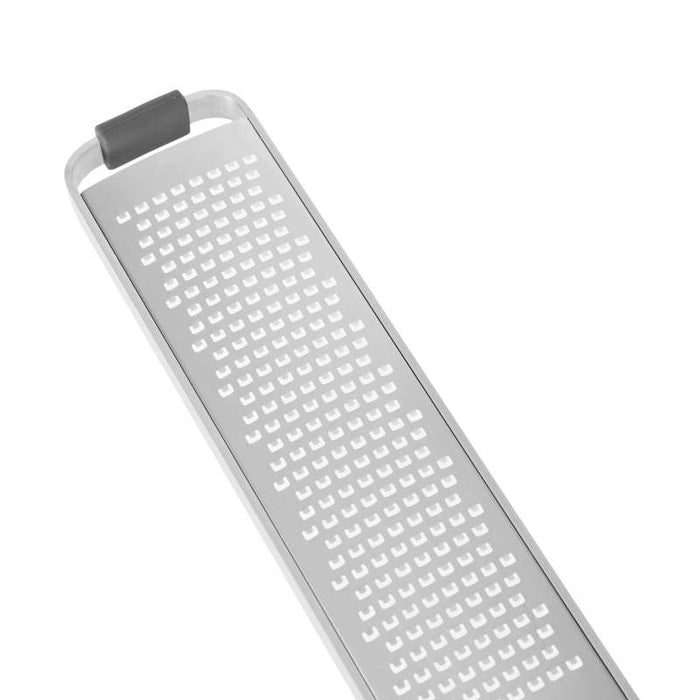 A close-up of a Full Circle Zester, featuring a stainless steel rectangular shape with small square holes. Ideal for grating hard cheeses and citrus zest, it has a minimalist design with a rubber-gripped handle against a white background.